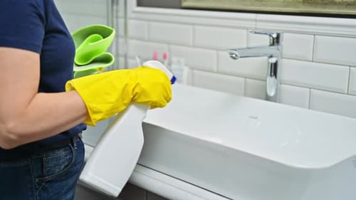 Woman Cleaning Bathroom Sink with Spray Bottle