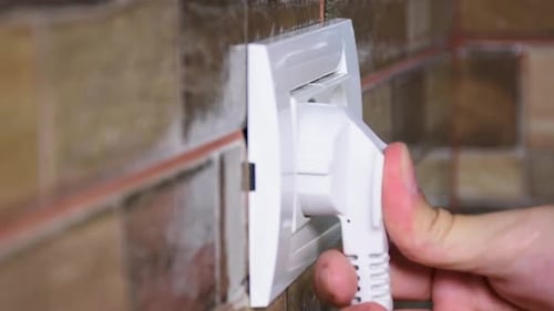 Side view of woman hand plugging and unplugging from the wall power socket.