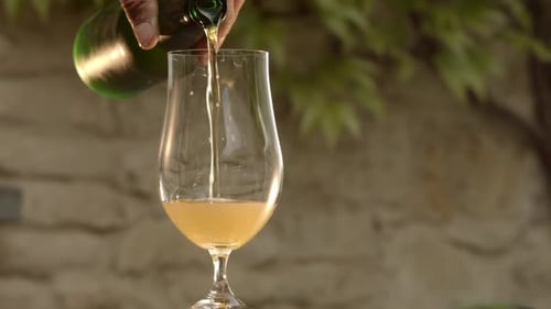 Glass of beer filled perfectly from green bottle. Slow motion copy space