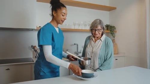 Woman in Scrubs Serving Food to Senior Woman