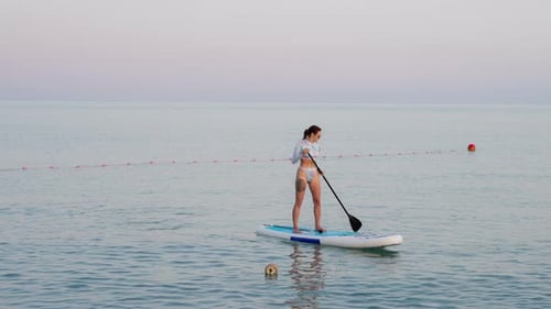 Woman Paddle Boarding on a Clear Ocean Day