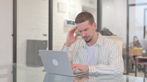 Man in Office Experiences Headache While Typing