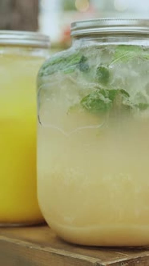 A Row of Jars with Various Fruit Juices on a Wooden Table Closeup Vertical Video