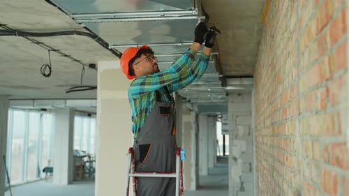 Construction Worker Securing Ceiling Hardware in Concrete Room