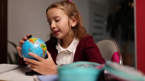 Child Studying Globe at Desk