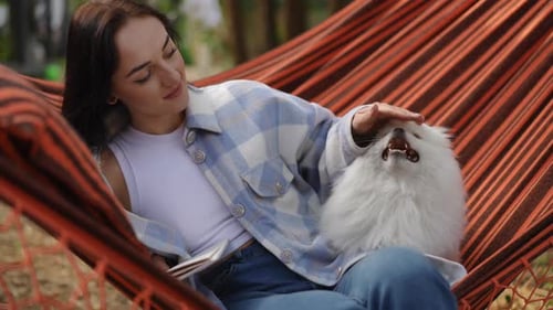Woman Relaxes in Hammock with Pet Dog