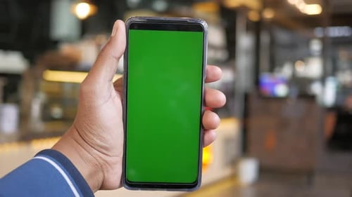 Young Man Hand Using Smart Phone with Green Screen at Cafe