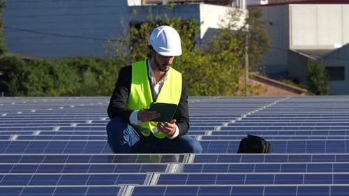 Engineer Inspects Solar Panels with Tablet on Roof