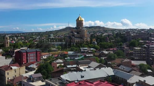 Aerial: Tbilisi city reveal, Metekhi Church in background, Georgia capital