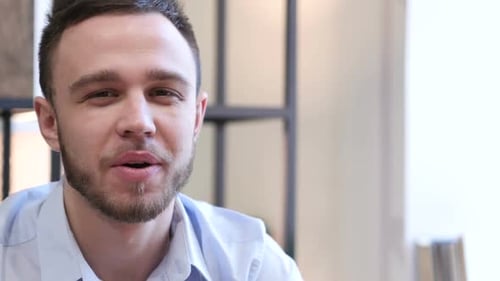 Young Man Waving and Talking to Camera