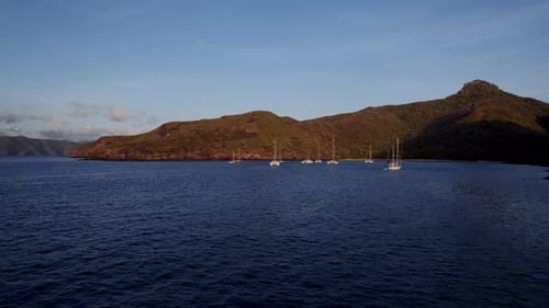 Sailboats Anchored In Calm Waters Near Coastal Hills