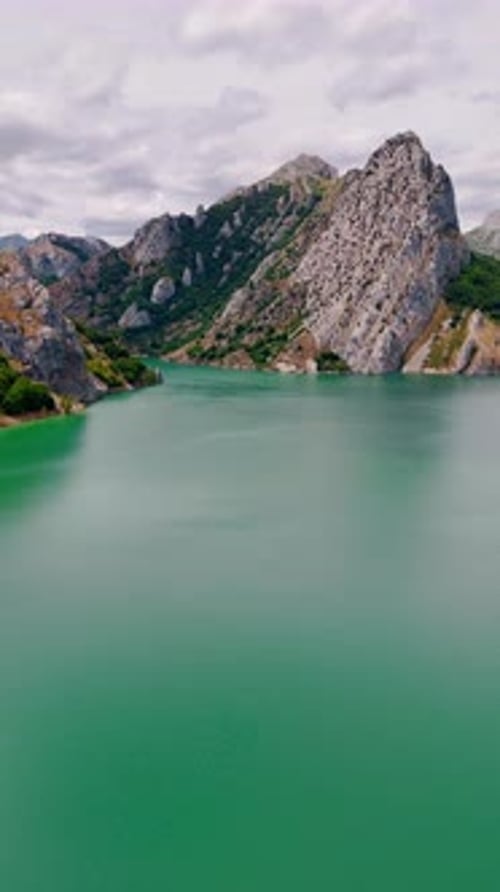 Turquoise Lake Surrounded by Green Mountains Aerial View