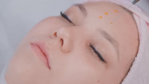 Aesthetician Applying Vitamin Serum of Facial Skin of Young Woman in Beauty Salon Closeup