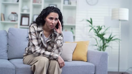 Woman Sitting On Couch Looking Distraught