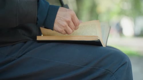 Man Reading a Book Outdoors On A Bench