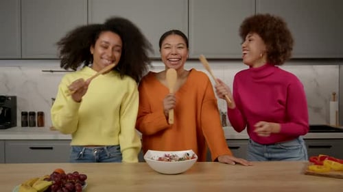 Cheerful Women Sing and Dance with Kitchen Utensils