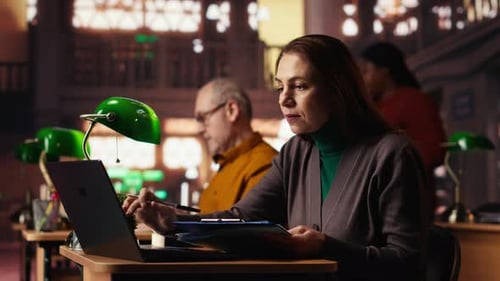Femme mûre intellectuelle transcrivant un texte académique à partir d'un ordinateur portable