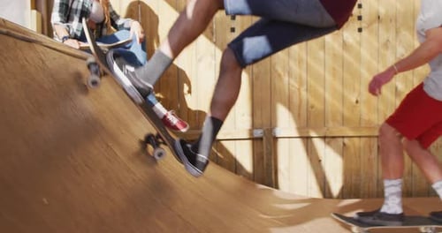 Video of legs of diverse female and male skateboarders in skate park