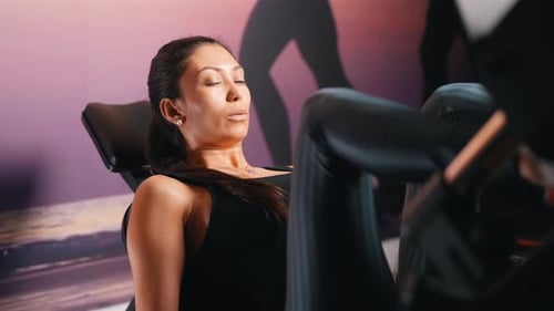 Young attractive sporty woman training legs muscles on leg press machine at the gym