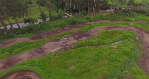 Drone tracks a dirtbike around a riverside motocross track