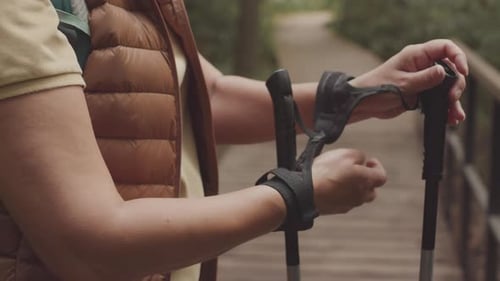 Une femme méconnaissable attachant des bâtons à ses mains avant la marche nordique