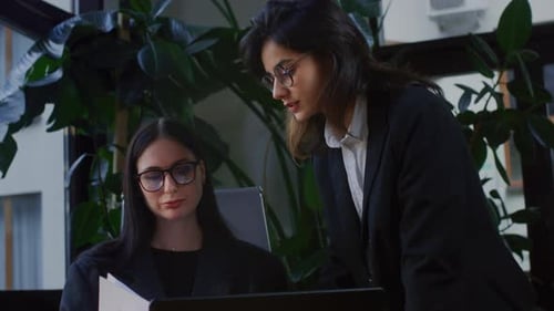 Two Girls in a Office Discuss Documents or a Project on Paper Businesswomen Create a Marketing Plan