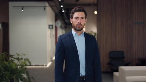 Man in Suit Stands in Office Hallway