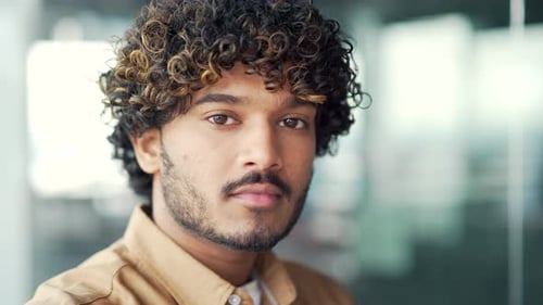 Close up portrait of young confident handsome man in modern office. Thoughtful male employee