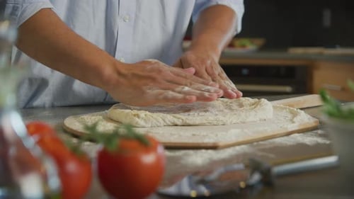 Chef Kneading Pizza Dough on Cutting Board in Kitchen