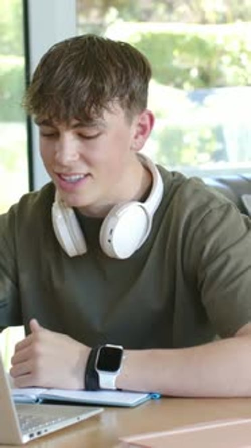 Vertical video: Male teen starting lesson on laptop, taking notes, animated notes syncing for exam