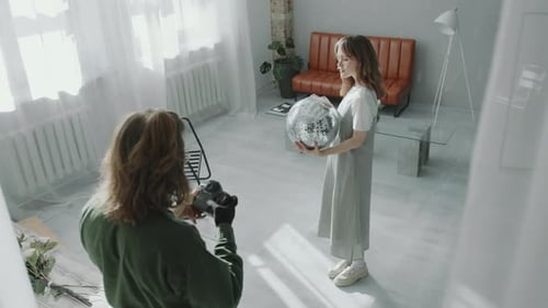 Photographer Capturing Images of Female Model Holding Disco Ball in Studio