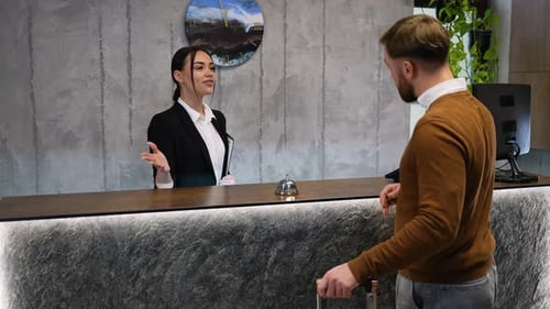Hotelrezeptionistin begrüßt den Gast beim Check-in an der Rezeption