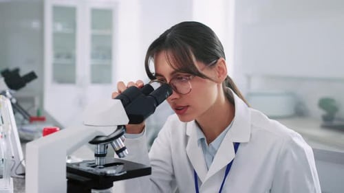 Young Woman Using Microscope in Modern Lab