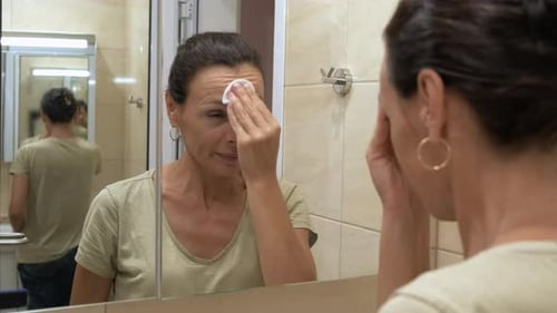 A cute female cleans her face in the bathroom