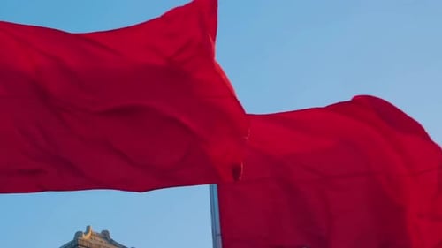 Bright Red Flags Waving Against Blue Sky