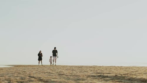 A Family Enjoying a Stroll on the Beach While Watching the Beautiful Sunset Glow