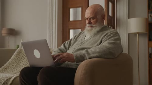 Senior Man Using Laptop in Armchair at Home