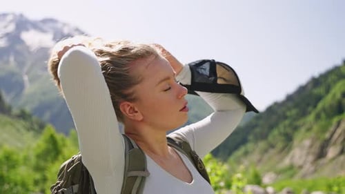 Woman Puts Hair Up on Mountain Adventure