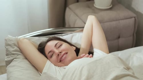 Woman Wakes Up and Stretches in Bed
