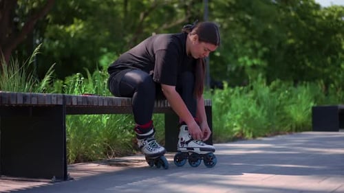young hipster girl puts on roller skates in skate park before starting skating street extreme sport
