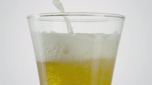 Light Beer Pours Into Glass on White Background