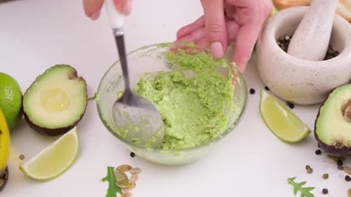Mashing Avocado in Glass Bowl for Fresh Guacamole