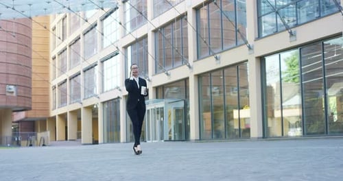 Portrait of Multiethnic Adult Businesswoman Using Smartphone While Walking on Street in a Big City