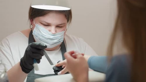 Manicurist Filing Fingernails in a Nail Salon