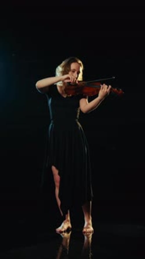 Woman Plays Violin in Dark Setting