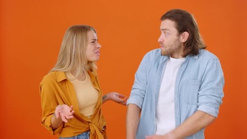 Frustrated Couple Arguing on Orange Background