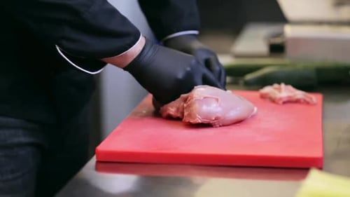 Chef masculino cortando habilmente carne de frango na cozinha do restaurante em câmera lenta
