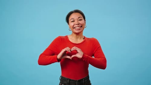 Woman Smiling and Making Heart Shapes with Hands