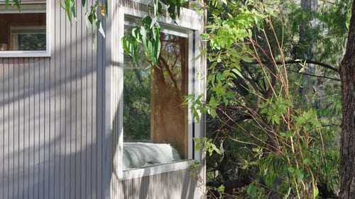 Cinematic view of tiny cabin bedroom window looking out into the forest.