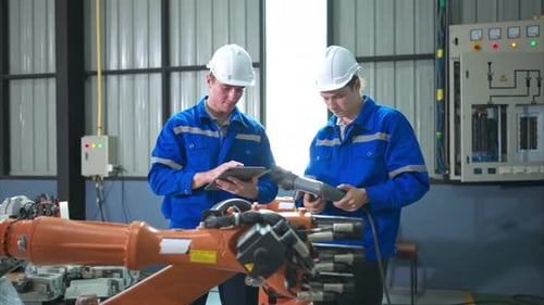Engineer and technician working with robot arm in factory. Industry and engineering concept.